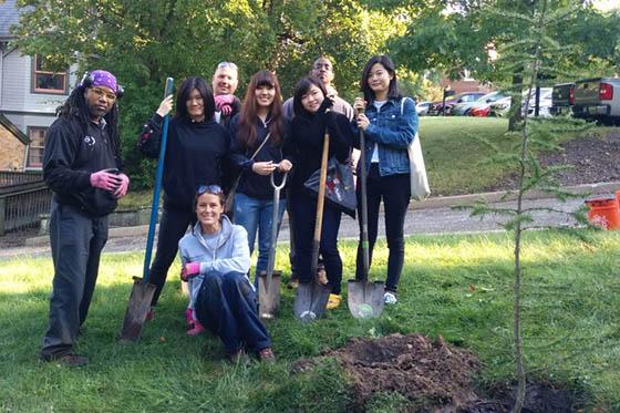 Photo of a group of Chatham University students and staff members posing around a tree they planted